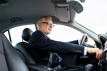 Image showing happy senior businessman starting car and driving