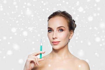 Image showing woman holding syringe with injection over snow