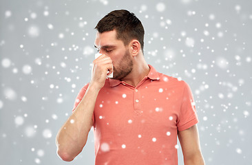 Image showing sick man with paper wipe blowing nose over snow