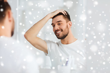 Image showing happy young man looking to mirror at home bathroom