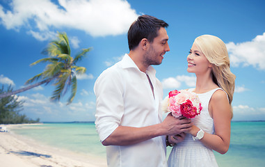 Image showing happy couple with flowers over beach background