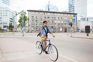 Image showing young hipster man with bag riding fixed gear bike