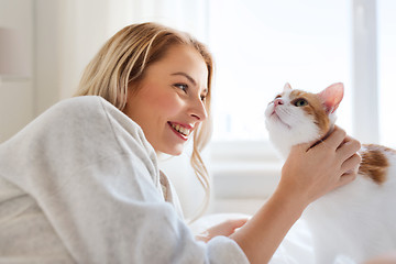 Image showing happy young woman with cat in bed at home