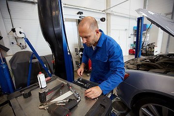 Image showing mechanic man with wrench repairing car at workshop