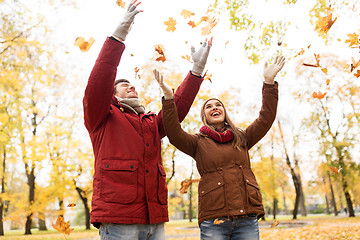 Image showing happy young couple throwing autumn leaves in park