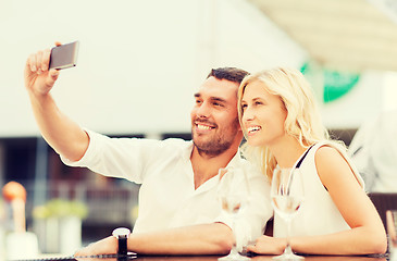 Image showing happy couple taking selfie with smartphone at cafe