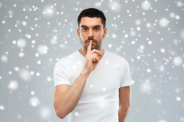 Image showing young man making hush sign over snow background