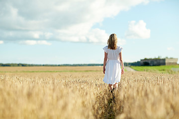 Image showing young woman in white dress walking along on field