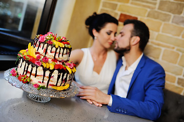 Image showing bride and groom kissing on the background of a wedding cake