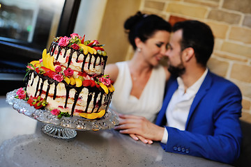 Image showing bride and groom kissing on the background of a wedding cake
