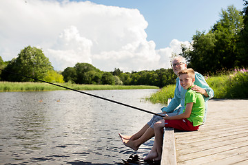 Image showing grandfather and grandson fishing on river berth