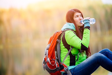 Image showing Brunette drinking water with backpack sitting close-up