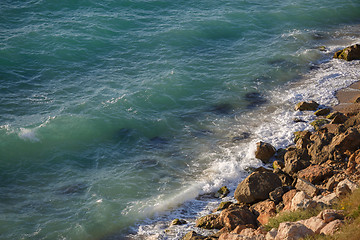 Image showing Rocky cliff and lazy lapping turquoise waves