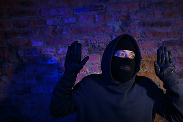 Image showing Surprised burglar standing against wall