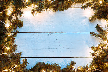 Image showing Christmas wooden background with fir-tree branches and lightbulb