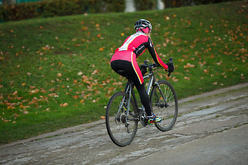 Image showing Sport young woman in tracksuit riding bicycle in early autumn