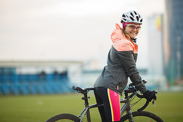 Image showing Portrait of smiling female bicyclist in tracksuit outdoors