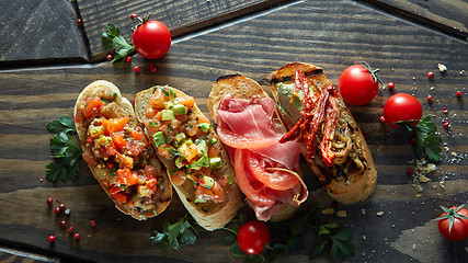 Image showing Various of mini bruschetta with tomatoes, salmon, avocado, bacon, and basil butter