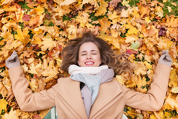 Image showing beautiful happy woman lying on autumn leaves