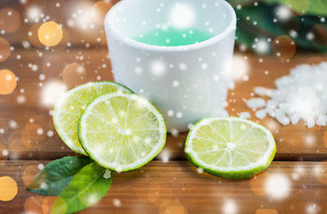 Image showing citrus body lotion in cup and limes on wood