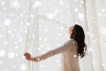 Image showing pregnant woman opening window curtains