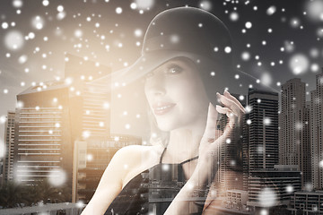 Image showing woman in black hat over city background and snow