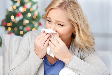 Image showing ill woman blowing nose to paper napkin