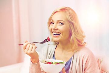 Image showing smiling middle aged woman eating salad at home