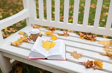 Image showing open book and coffee cup on bench in autumn park