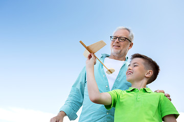 Image showing senior man and boy with toy airplane over sky