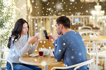 Image showing couple with smartphones drinking tea at cafe