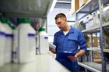 Image showing auto mechanic with oil and clipboard at car shop