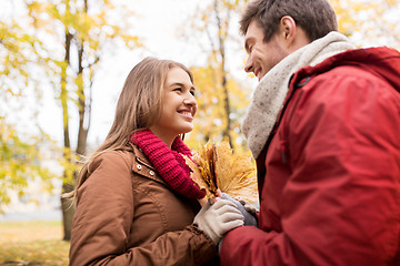 Image showing happy couple with maple leaves in autumn park