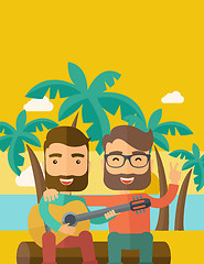 Image showing Two men playing a guitar at the beach