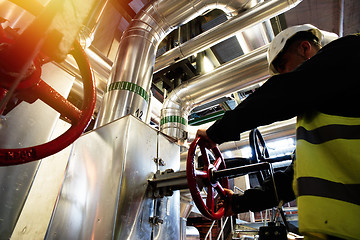 Image showing factory worker turning valve