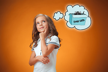 Image showing The cute thoughtful little girl on orange background