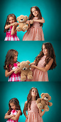 Image showing The two cute little girls on blue background with Teddy bear