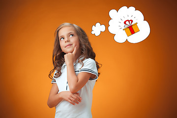 Image showing The cute thoughtful little girl on orange background