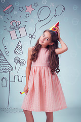 Image showing The cute cheerful little girl with festive cap on gray background