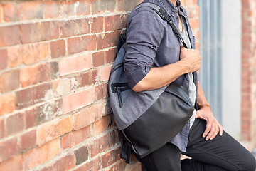 Image showing close up of man with backpack standing at wall