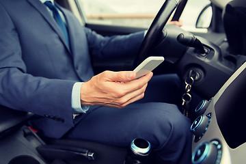 Image showing close up of man with smartphone driving car