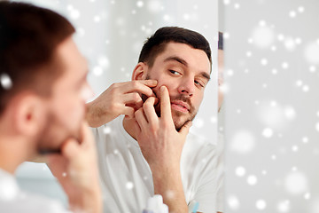 Image showing man squeezing pimple at bathroom mirror