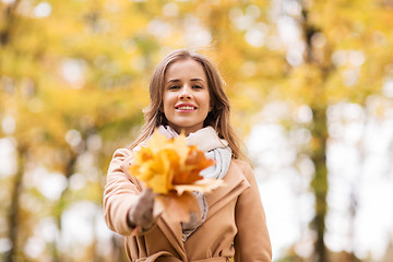 Image showing beautiful woman with maple leaves in autumn park