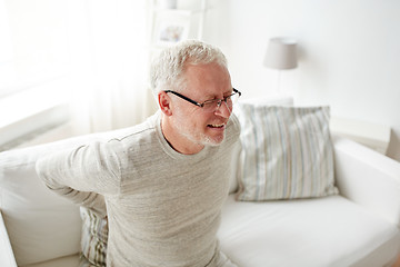 Image showing unhappy senior man suffering from backache at home