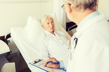 Image showing senior woman and doctor with clipboard at hospital