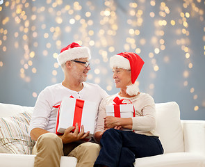 Image showing happy senior couple in santa hats with gift boxes