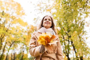 Image showing beautiful woman with maple leaves in autumn park