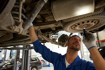 Image showing mechanic man with flashlight repairing car at shop