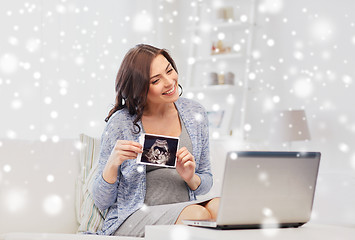 Image showing happy pregnant woman with ultrasound image at home