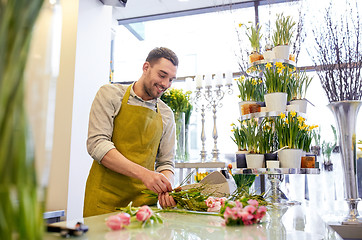 Image showing smiling florist man making bunch at flower shop